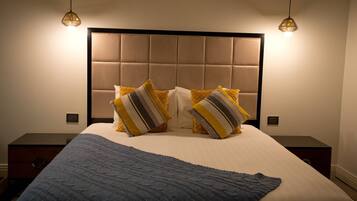 A bed with a tufted headboard, two bedside tables, and a blue throw blanket.