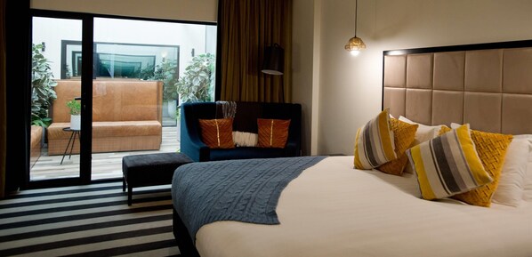 Una habitación de hotel con cama, una silla, un ventanal y vistas al exterior.