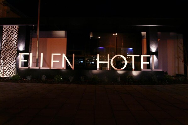 Exterior do Ellen Hotel com letreiros iluminados.
