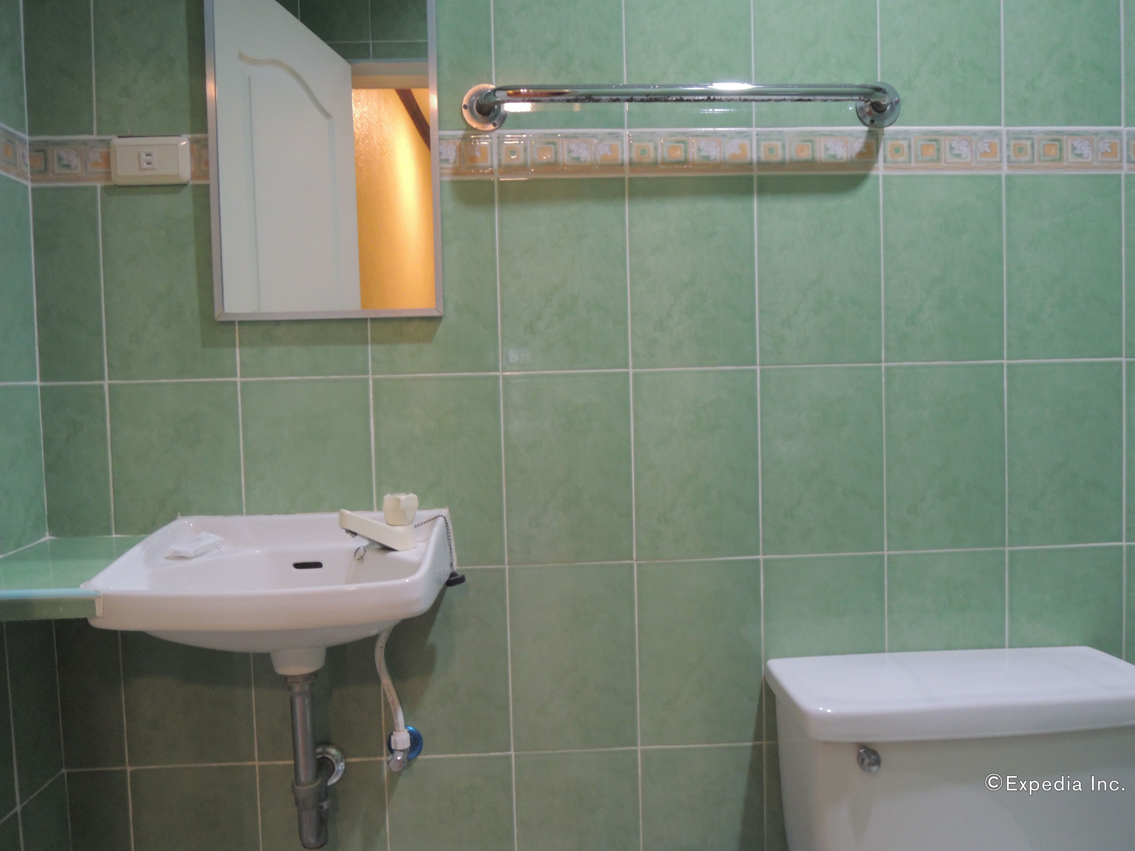 A bathroom with a white sink, a toilet, and a handrail.