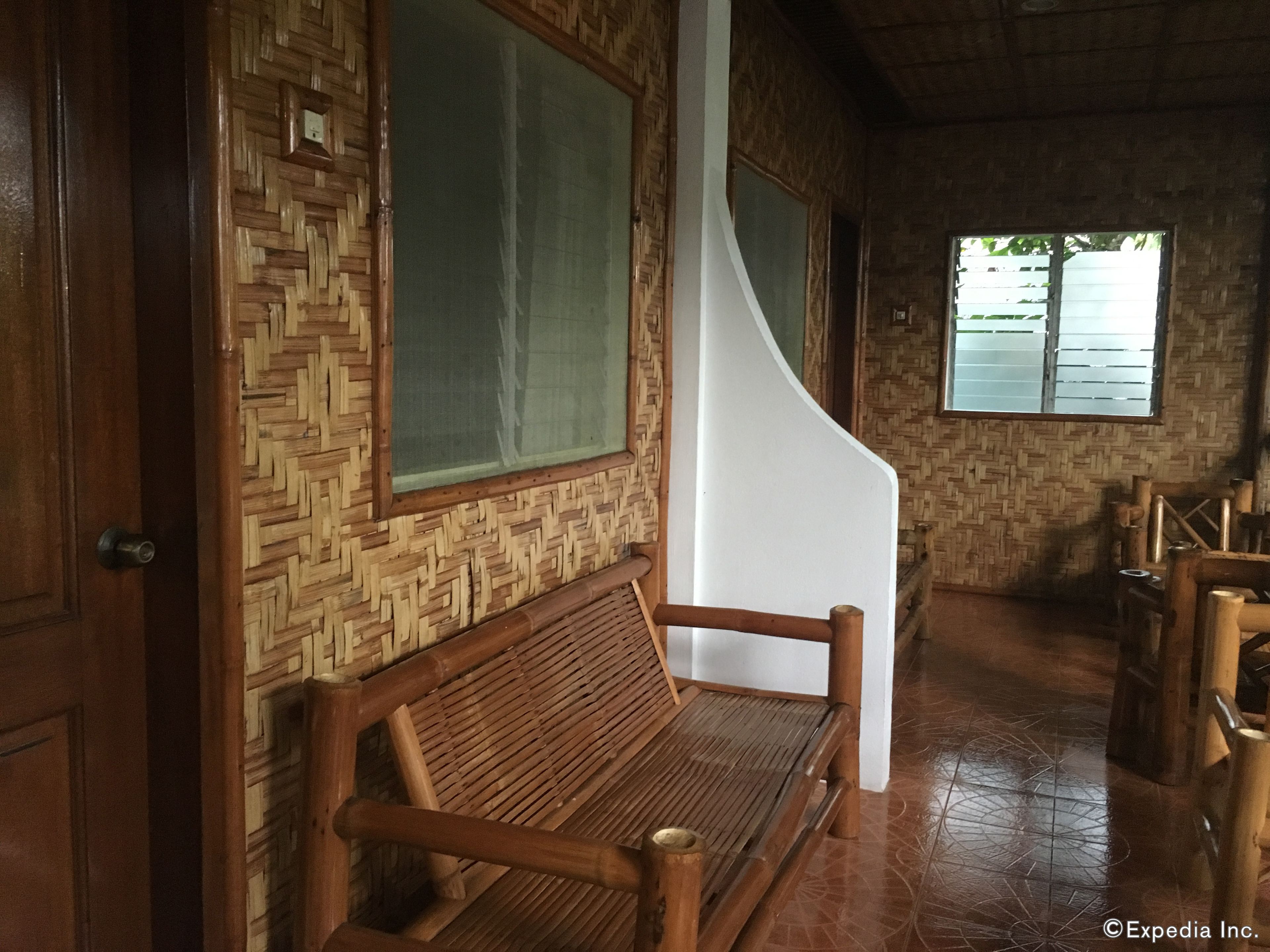 A wooden bench with a woven backrest, a large window, and a woven wall pattern.