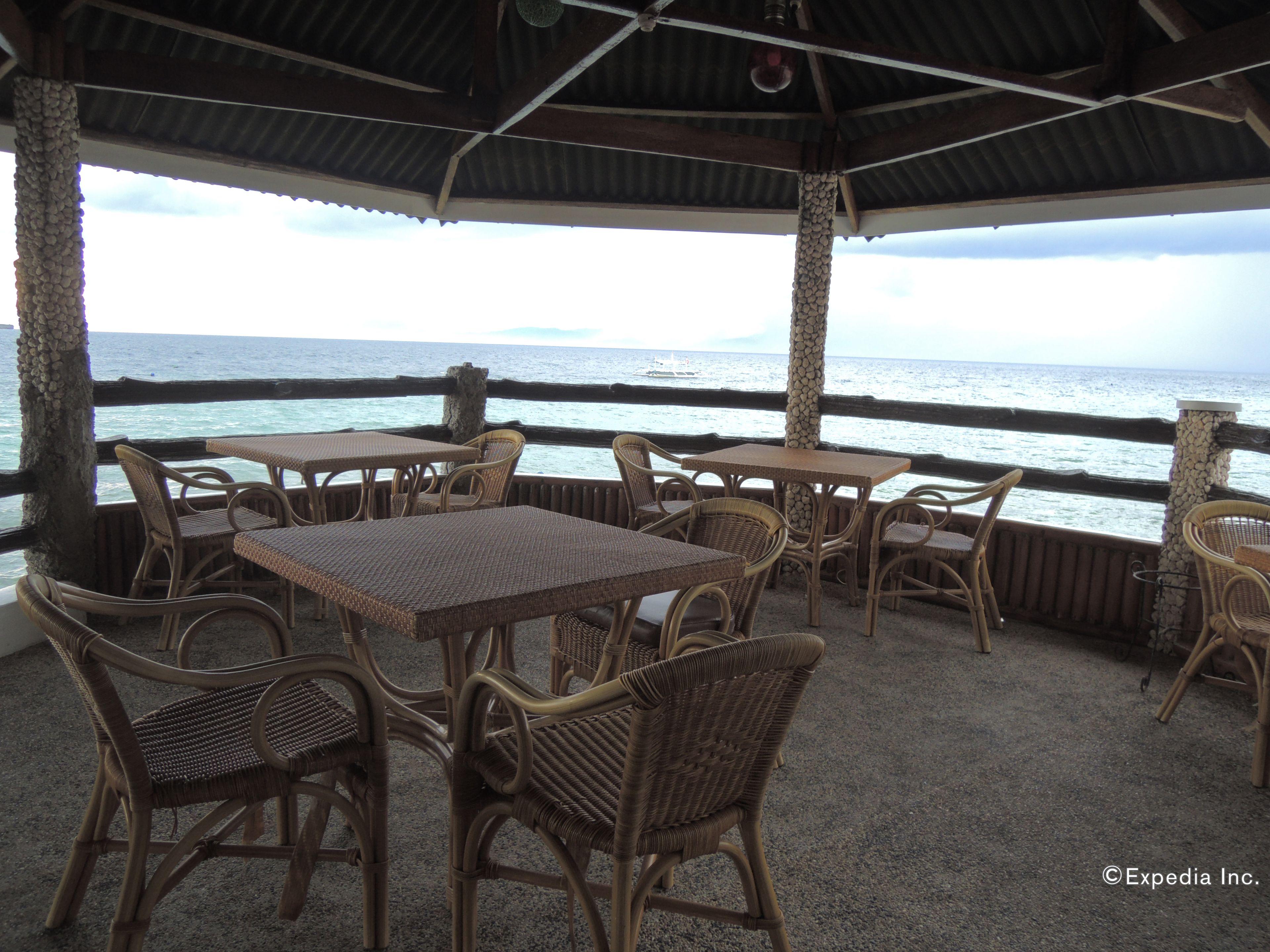 An outdoor seating area with wicker furniture and a view of the ocean.
