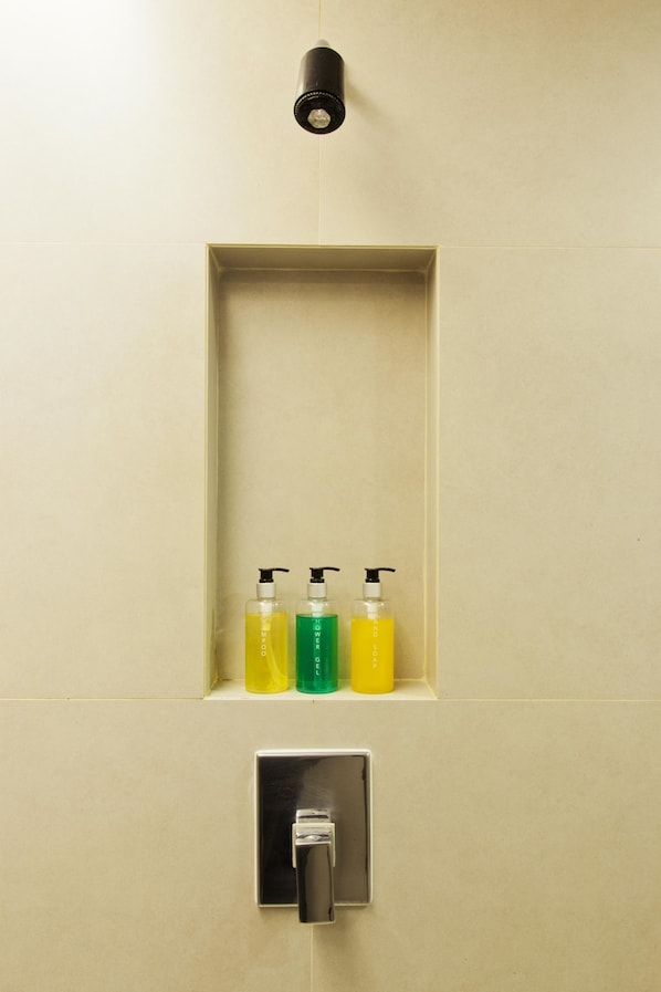 Une salle de bain avec une étagère sur laquelle sont posées trois bouteilles de savon liquide et un robinet en dessous.
