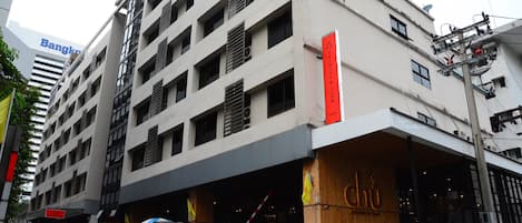 A multi-story building with a prominent entrance featuring a wooden facade and signage.