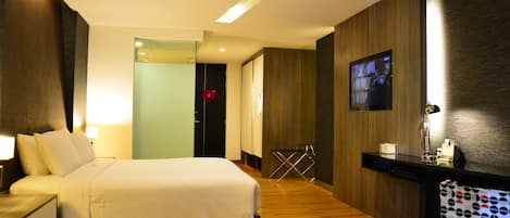 A hotel room with a bed, bedside table, TV, and a desk with a chair.