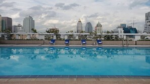 A swimming pool with lounge chairs and a city skyline in the background. - Trinity Silom Hotel (Bangkok)
