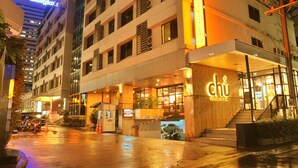 A multi-story hotel with a prominent 'Bangkok' sign, a 'chu' restaurant entrance, and a wet street.