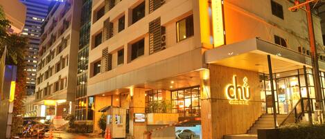 A multi-story hotel with a prominent 'Bangkok' sign, a 'chu' restaurant entrance, and a wet street.