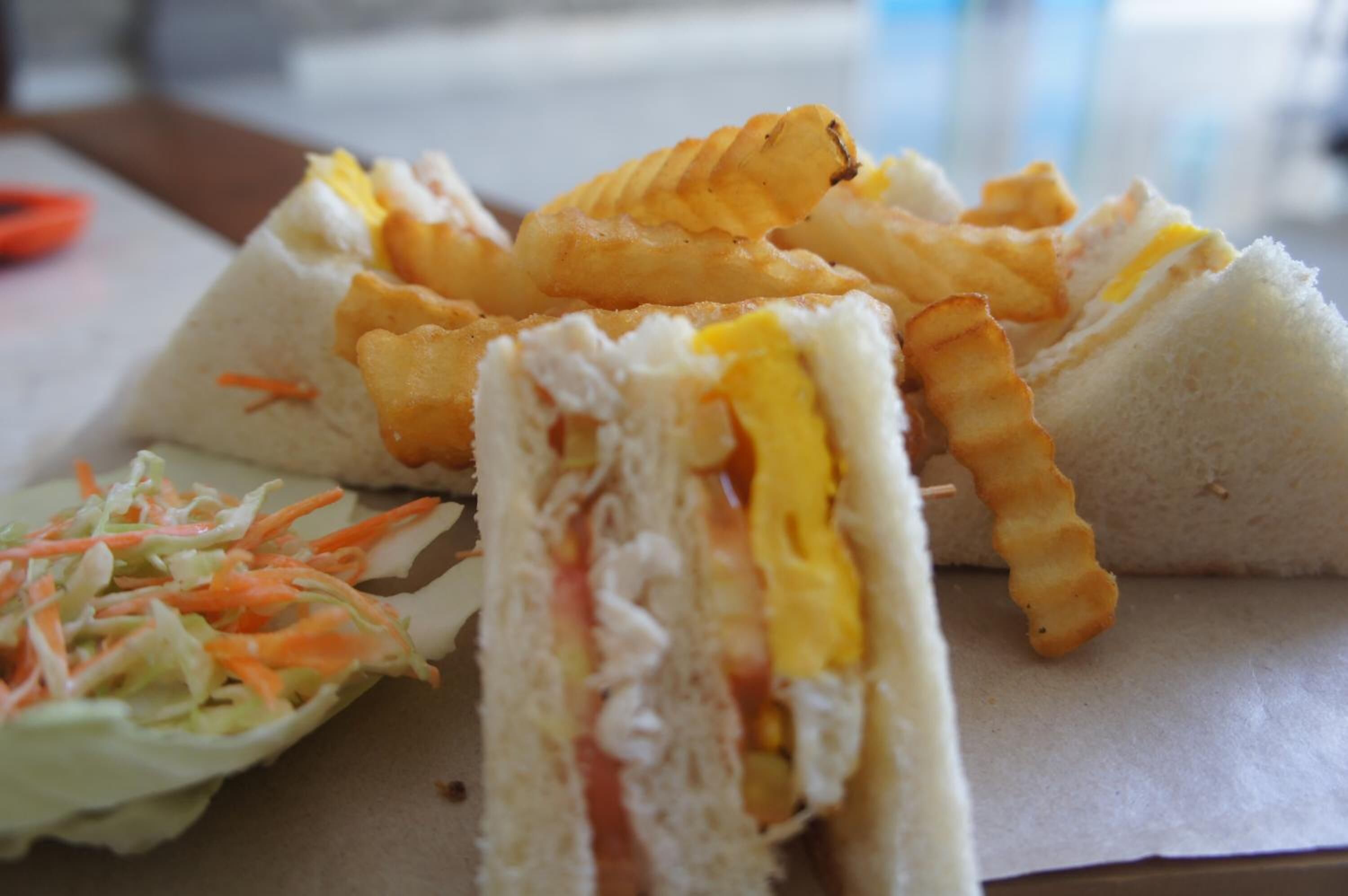 A sandwich with coleslaw and potato chips.