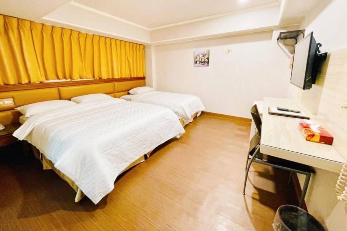 Una habitación de hotel con dos camas, un escritorio, una silla y una mesita.