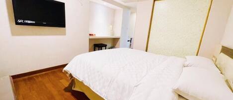 Habitación de hotel con cama, televisor montado en la pared, escritorio y una silla.