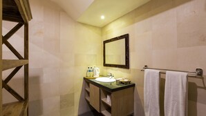 Un baño con tocador de madera, un lavamanos, un espejo y un perchero para toallas.