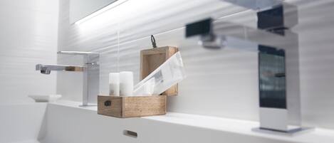 A modern bathroom with a sleek, minimalist design, featuring a white sink, a wooden soap dish, and a glass shower enclosure.