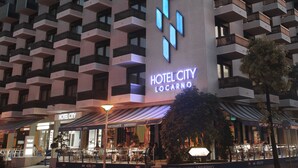 Un hôtel au design moderne, doté de balcons et d’une enseigne bien visible indiquant « HÔTEL CITY LOCARNO ».