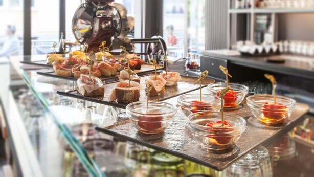 Un espace bar équipé d’une machine à café, d’un assortiment de hors-d’œuvre présentés sur un plateau, et de petits bols contenant différentes sauces.