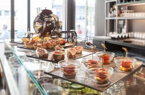 A bar area with a coffee machine, a variety of appetizers on a tray, and small bowls of sauces.