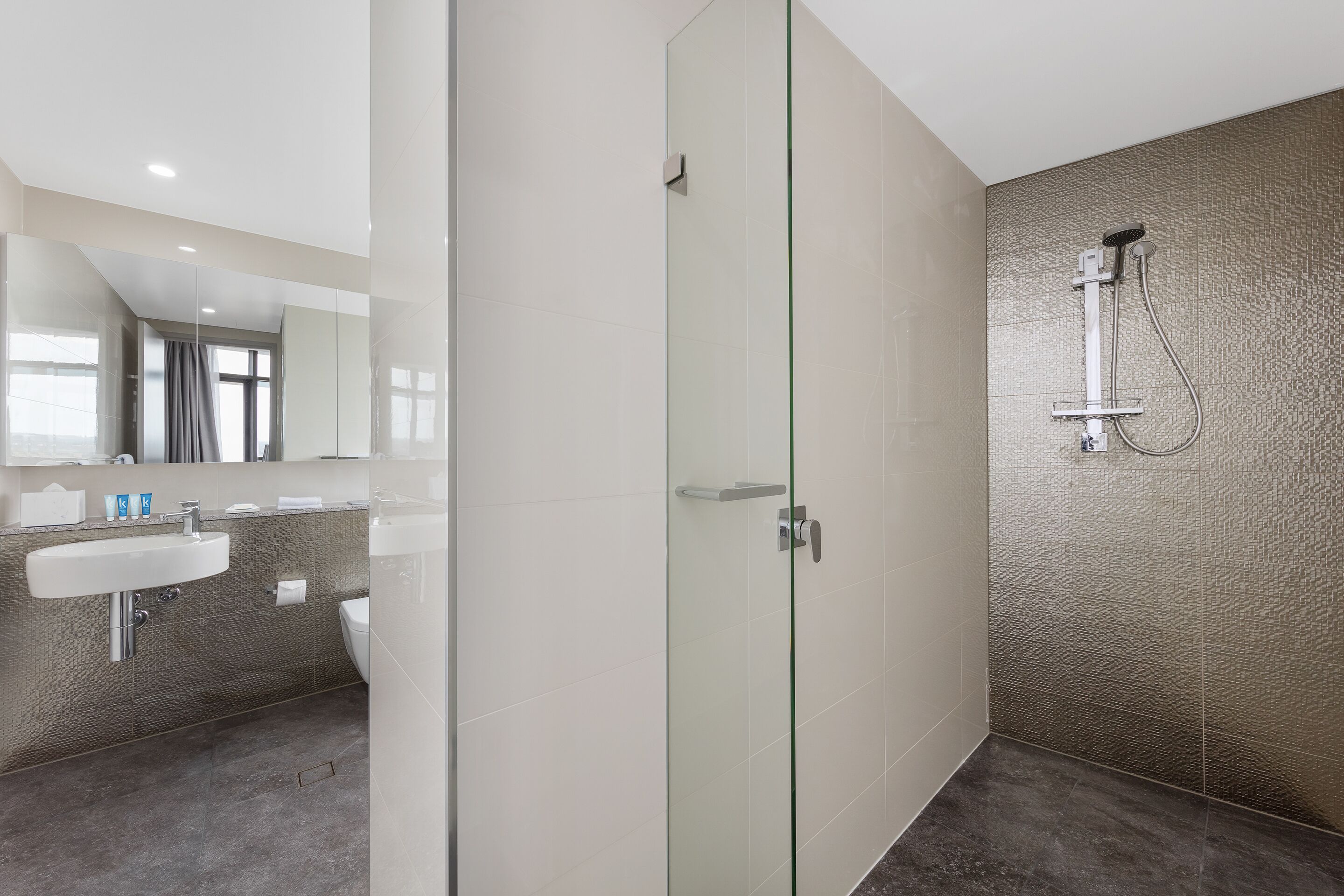 A modern bathroom with a glass-enclosed shower, a sink, and a mirror.