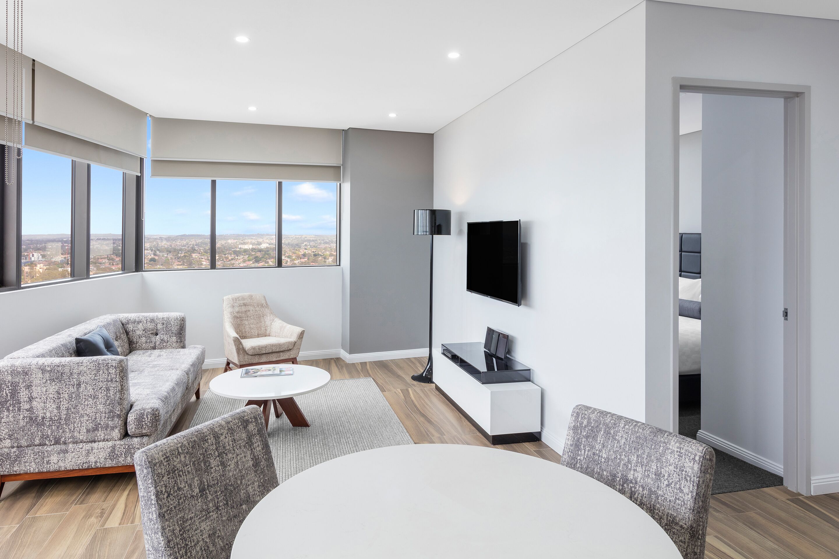 Una sala de estar moderna con un sofá, sillas, una mesa de centro y un televisor montado en la pared.