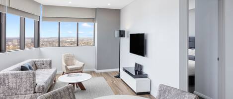 A modern living room with a sofa, chairs, a coffee table, and a TV mounted on the wall.