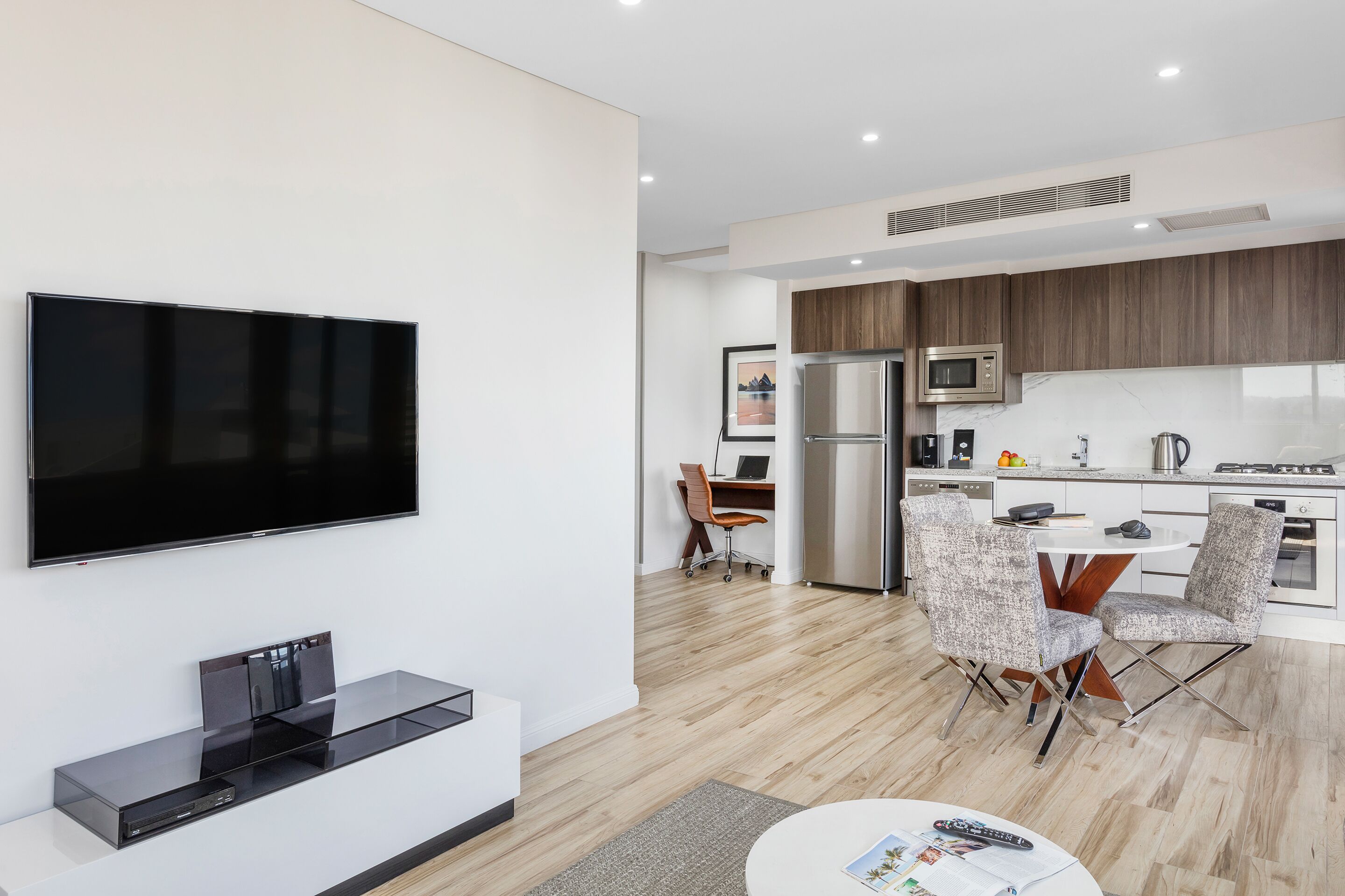 A modern living room with a flat-screen TV, a coffee table, and a seating area.