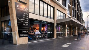 Um edifício moderno com um letreiro para o Meriton Dining Precinct e uma lista de restaurantes próximos.