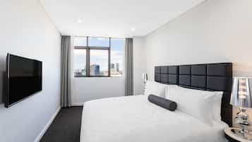 Une chambre d’hôtel avec un grand lit, un téléviseur à écran plat, une fenêtre donnant sur la ville et une table de chevet avec une lampe.