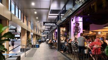 Un centre commercial moderne qui abrite un restaurant appelé « ALEX&Co. » et où l’on peut voir un escalier mécanique.