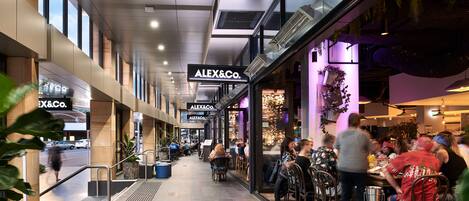 A modern shopping mall with a restaurant named 'ALEX&Co.' and a visible escalator.