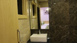 Ein Badezimmer mit einem weißen Waschbecken, dunklen Marmorwänden und einer Holztür.