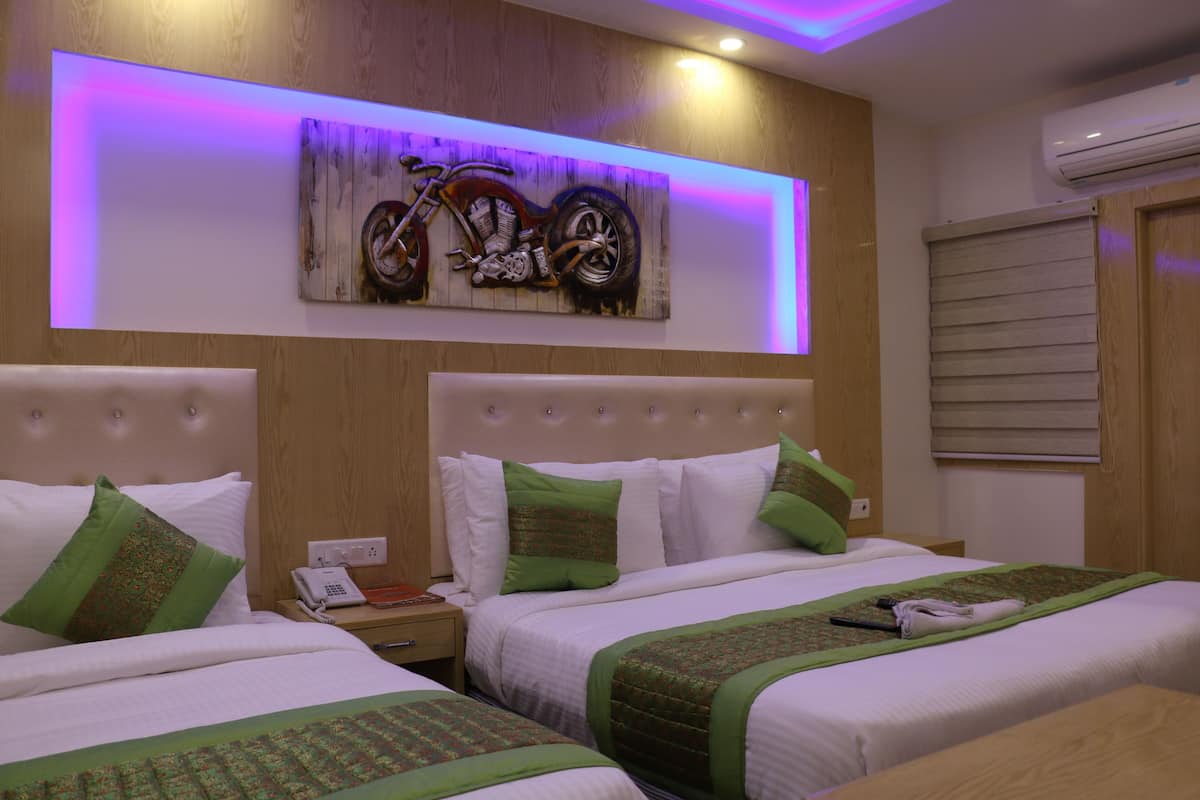 Ein Hotelzimmer mit zwei Betten, einem an der Wand hängenden Kunstwerk einer Motorradszene und einer Klimaanlage.