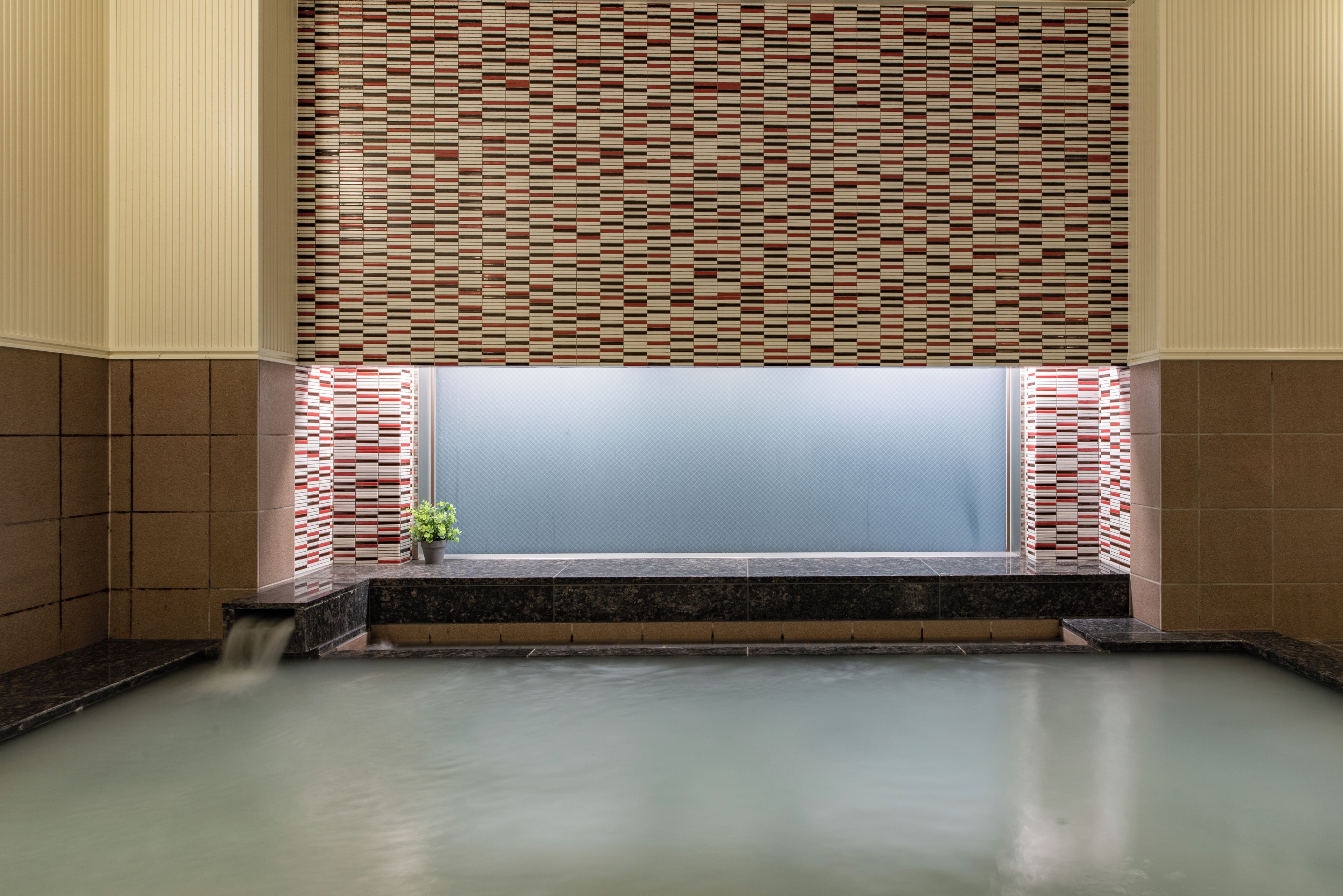 A spa area with a tiled wall, a bench, and a water feature.