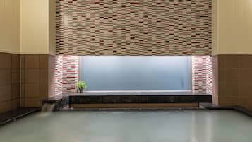 A spa area with a tiled wall, a bench, and a water feature.