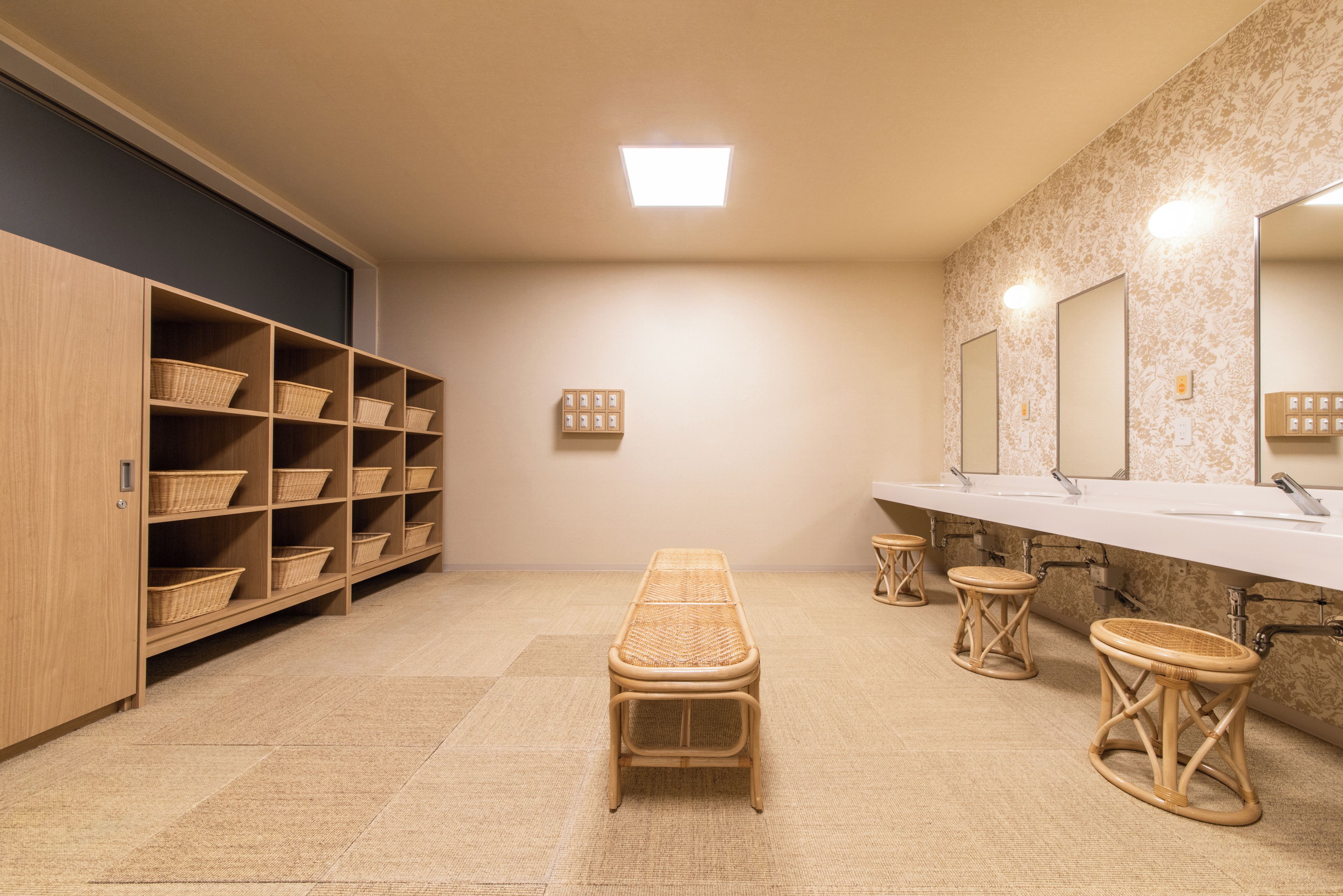 Une salle de bain avec un banc, des étagères avec des paniers, un miroir et un lavabo.
