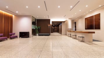 A spacious lobby with a reception desk, seating area, and a plant.