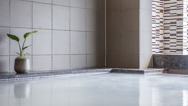 A clean, modern bathroom with a large mirror, a potted plant, and a tiled floor. - Hotel Vista Sendai (Sendai)