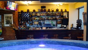 A bar area with a variety of liquor bottles, a television screen, and a decorative wall with jars.