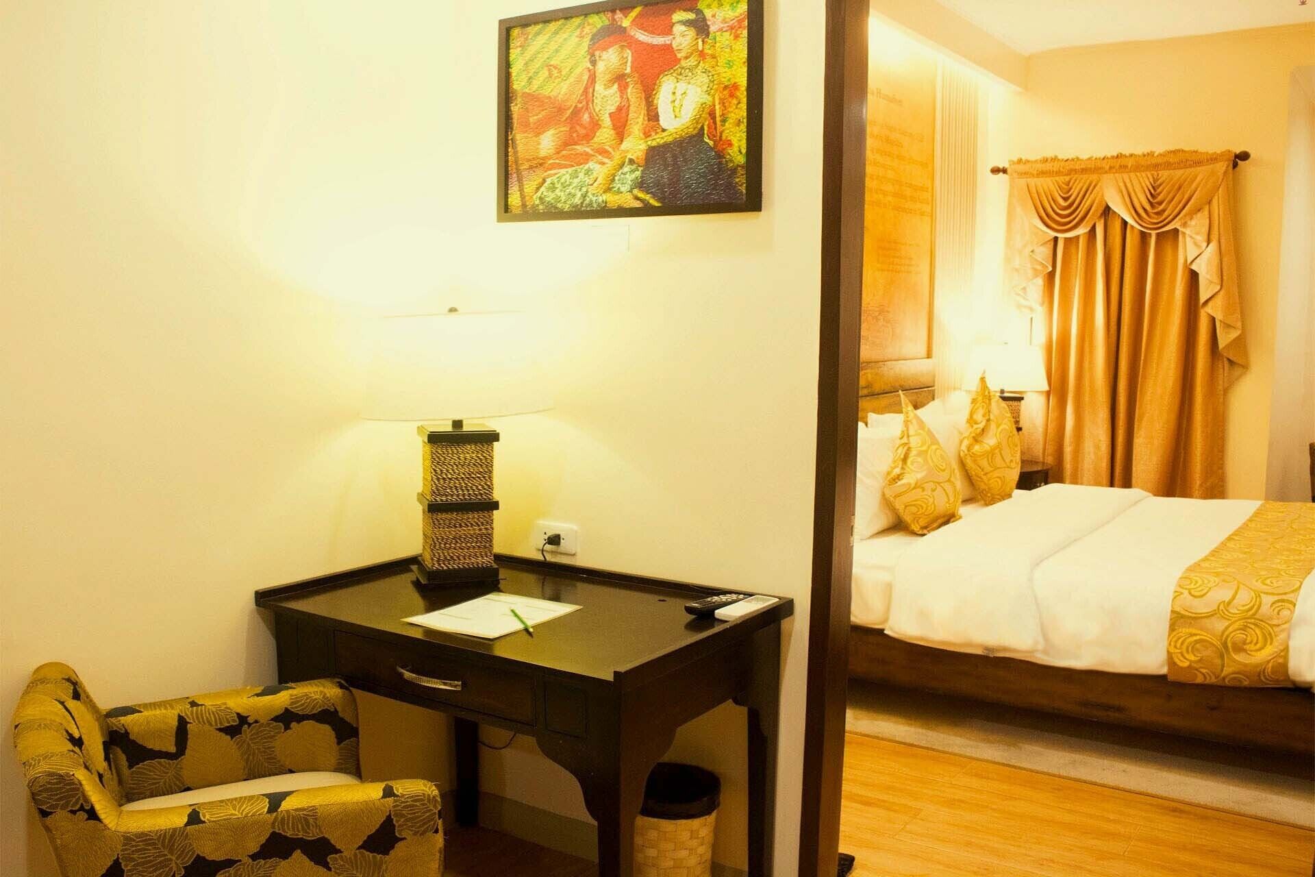 Una habitación de hotel con escritorio, silla, cama y un cuadro en la pared.