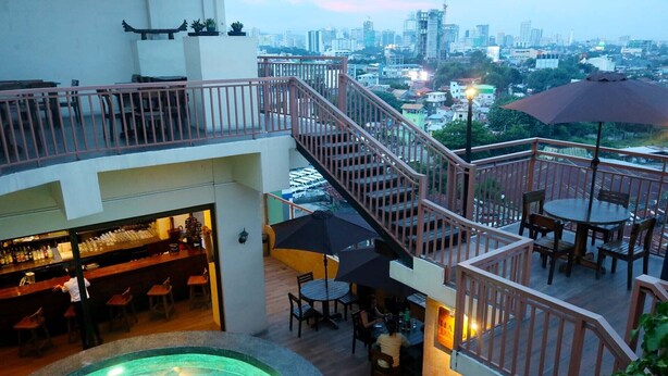 An indoor/outdoor bar area with a pool, seating, and a staircase leading to an upper level.