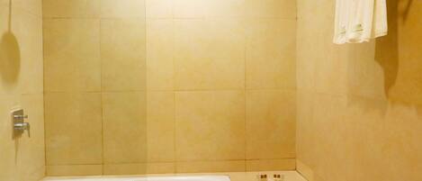 Un baño con bañera, ducha y barra para toallas.