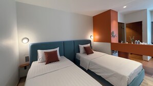 Habitación de hotel con dos camas, baño y una pequeña zona de estar.