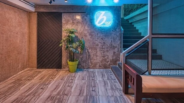 Un intérieur moderne avec un plancher en bois, une plante en pot, un panneau lumineux au néon et un escalier.