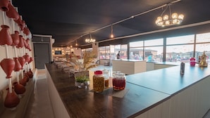 Zona bar moderna con un lungo bancone, ceramiche decorative e ampie finestre che offrono vista all'esterno.
