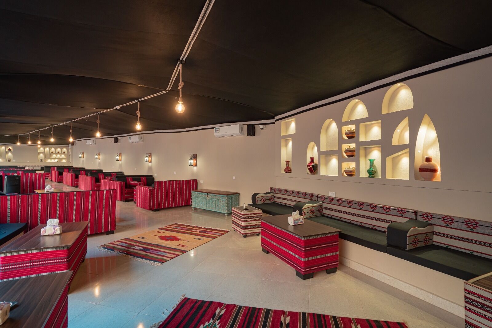 A spacious lounge area with red and green seating, a long counter, and decorative wall niches.