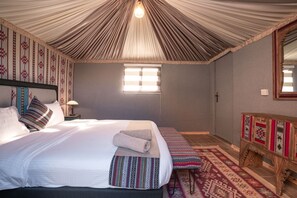 A bedroom with a bed, a bench, a nightstand, and a mirror. - Rahayeb Desert Camp (Wadi Rum)