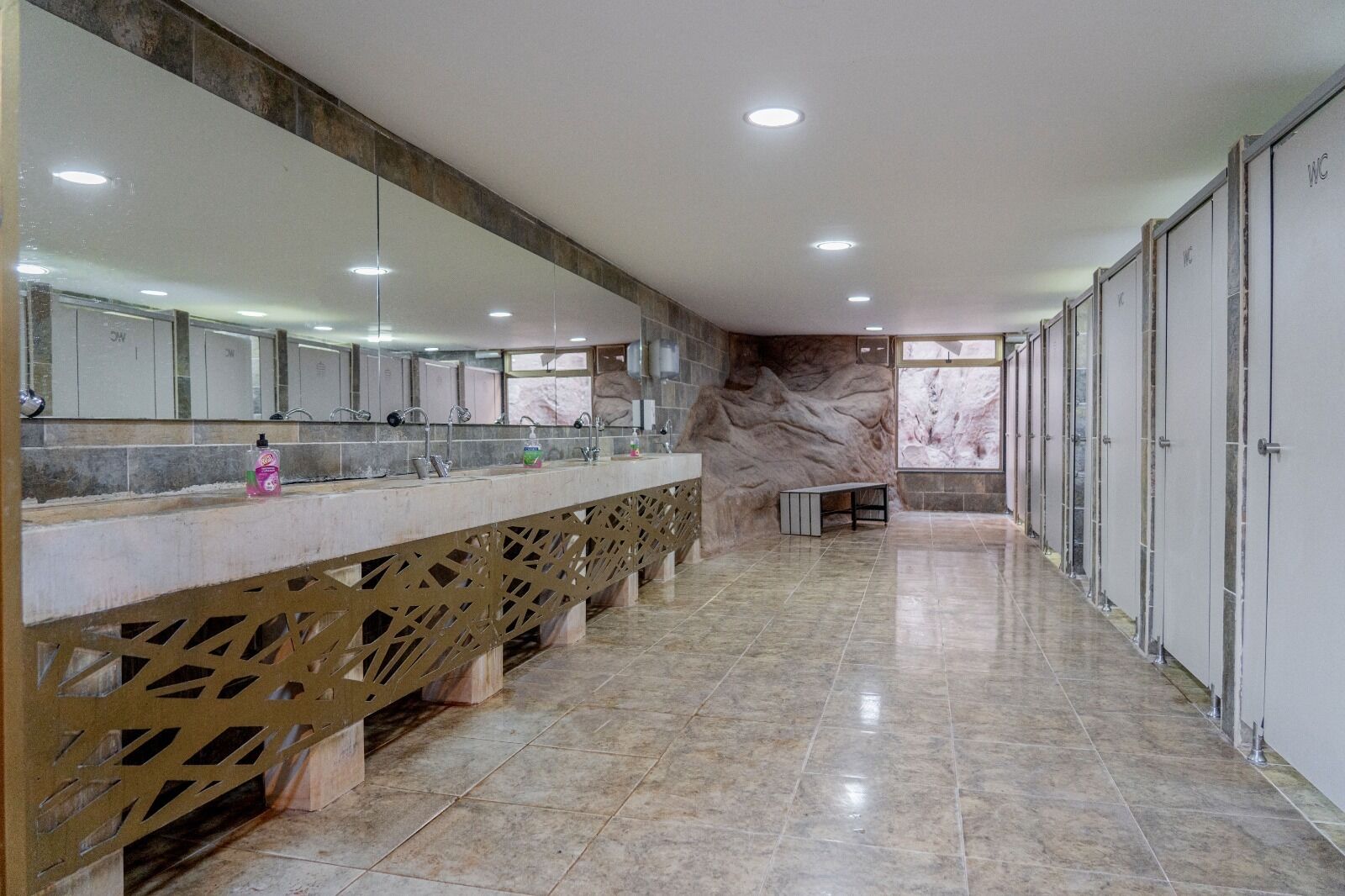 Casa de banho moderna com piso de mármore, toucador comprido com espelho e vários armários.