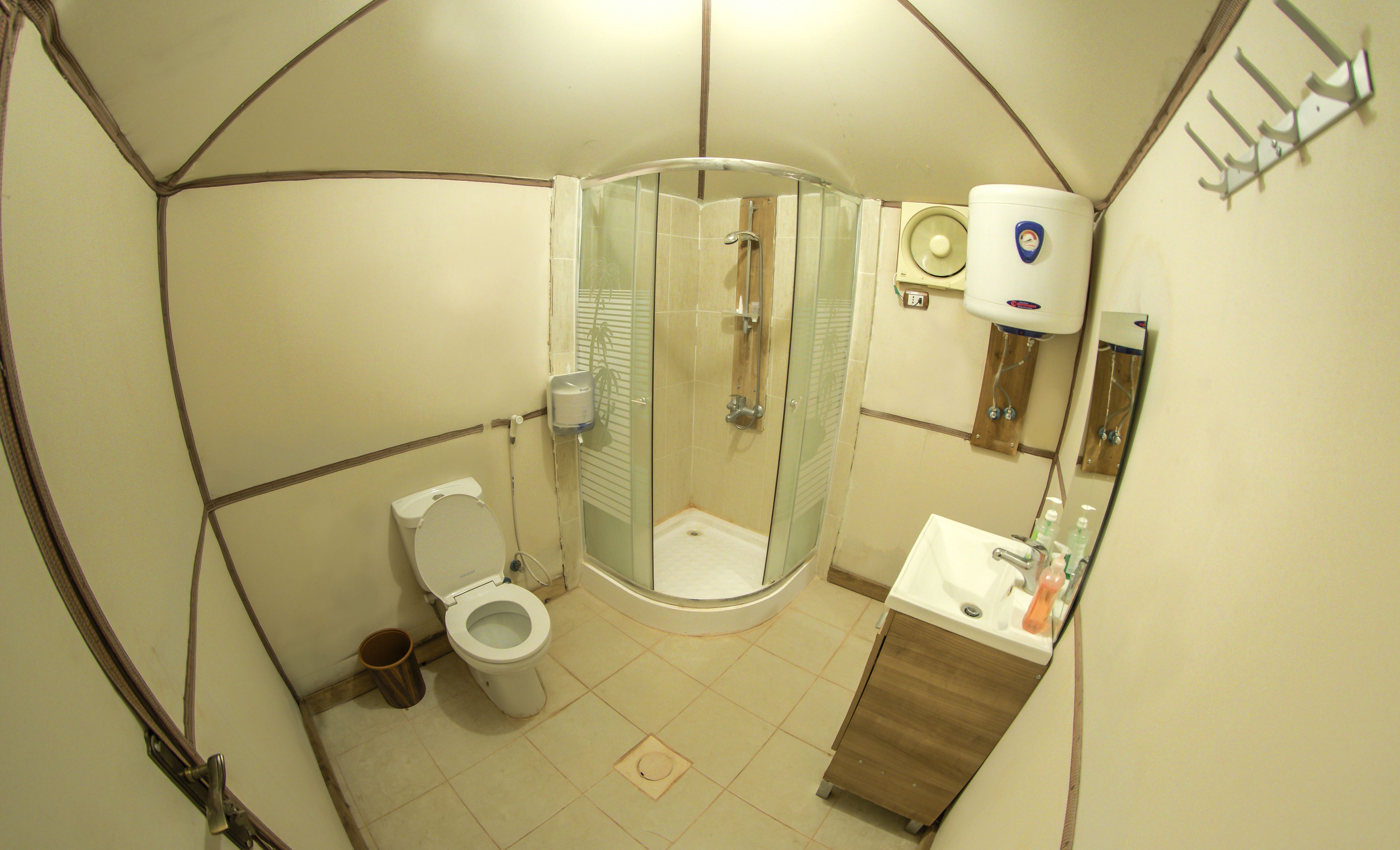 A compact bathroom with a glass-enclosed shower, a toilet, and a sink with a mirror.