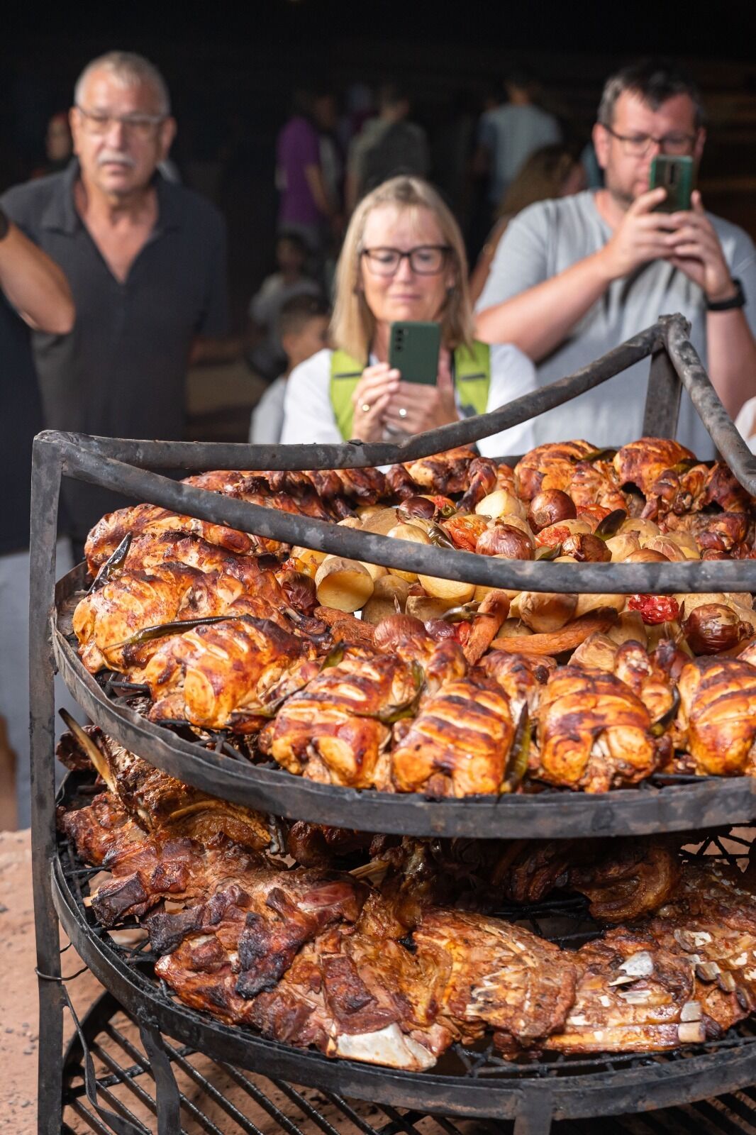 Una parrilla grande al aire libre con varios tipos de carne y verduras asándose.