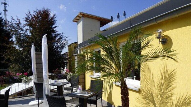 Un patio al aire libre con una mesa y sillas, una palmera y un edificio amarillo al fondo.