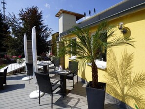 Un patio al aire libre con una mesa y sillas, una palmera y un edificio amarillo al fondo.