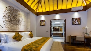 Ein Hotelzimmer mit einem großen Bett, einem Schreibtisch und einem durch eine geöffnete Tür einsehbaren Badezimmer.